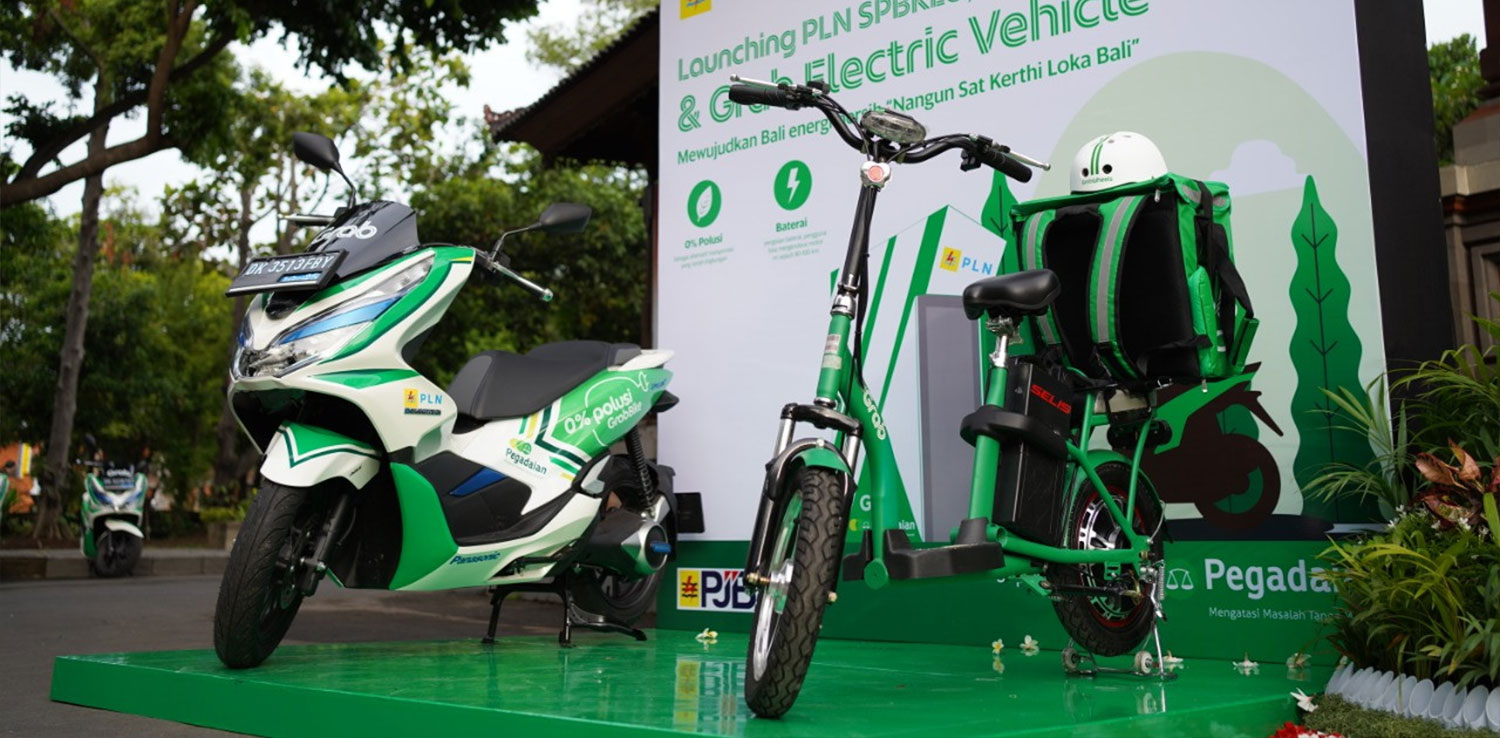 A green and white painted motorbike and a green monoped stand on a green stage with Grab Electric Vehicle written on the backdrop.