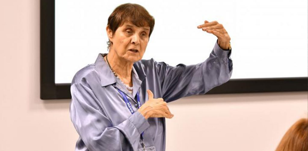 lena dominelli wears a purple shirt, giving a lecture