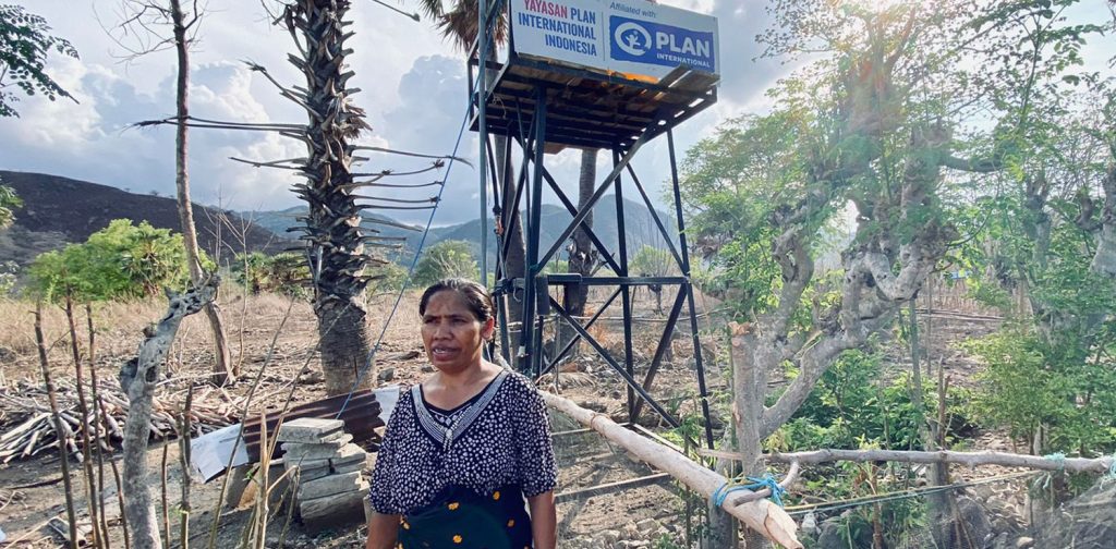 A mama (mother) in front of one of the clean water facilities installed by Plan Indonesia