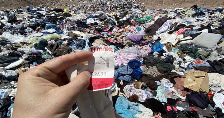 a heap of discarded clothing on a desert with a price tag attached to an unused item in the foreground