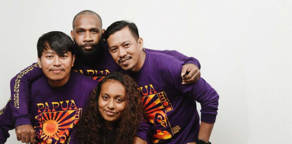three men and one woman posing together closely in purple jendela Papua t-shirts, The four winners of Jendela Papua project