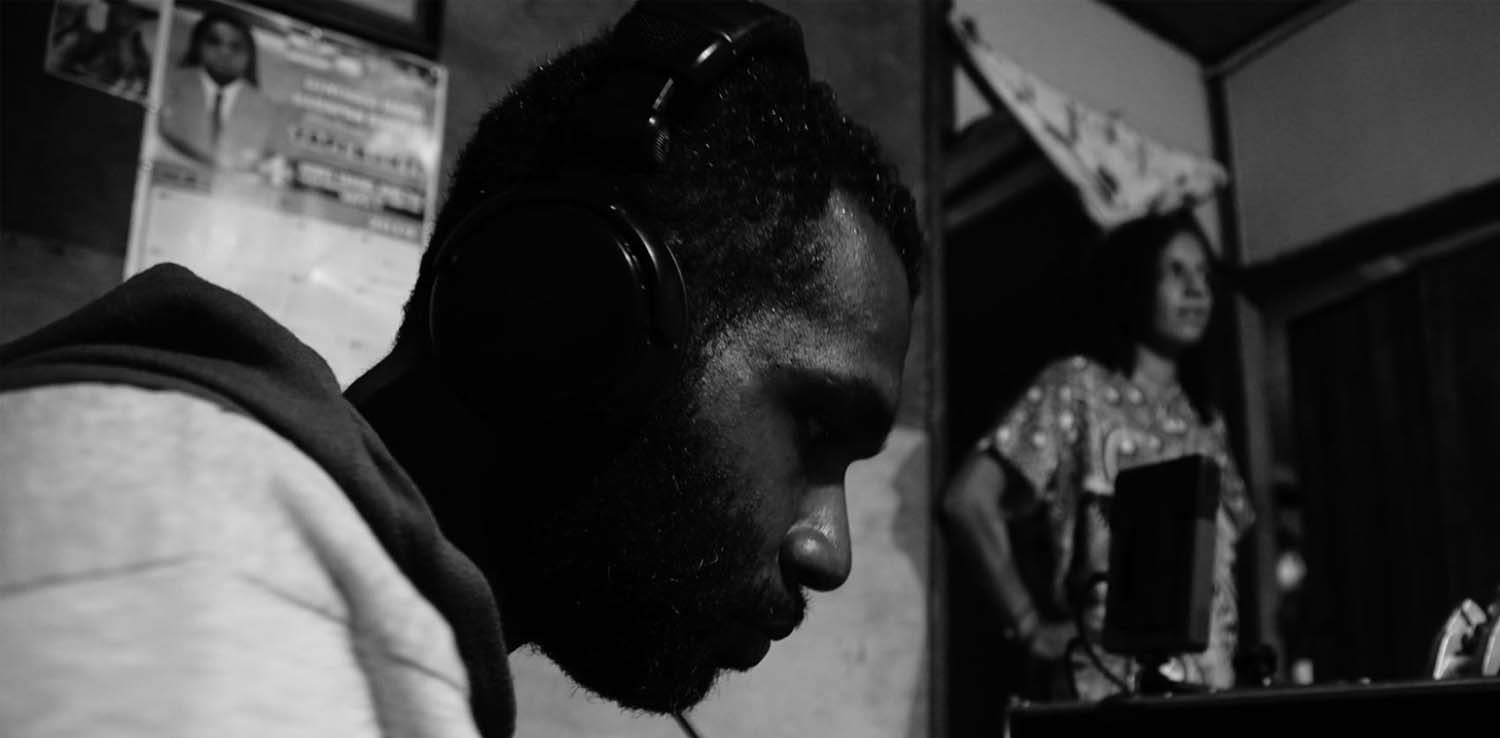 a man with a headset looking at the camera viewer at the film set of Orpa for jendela papua project