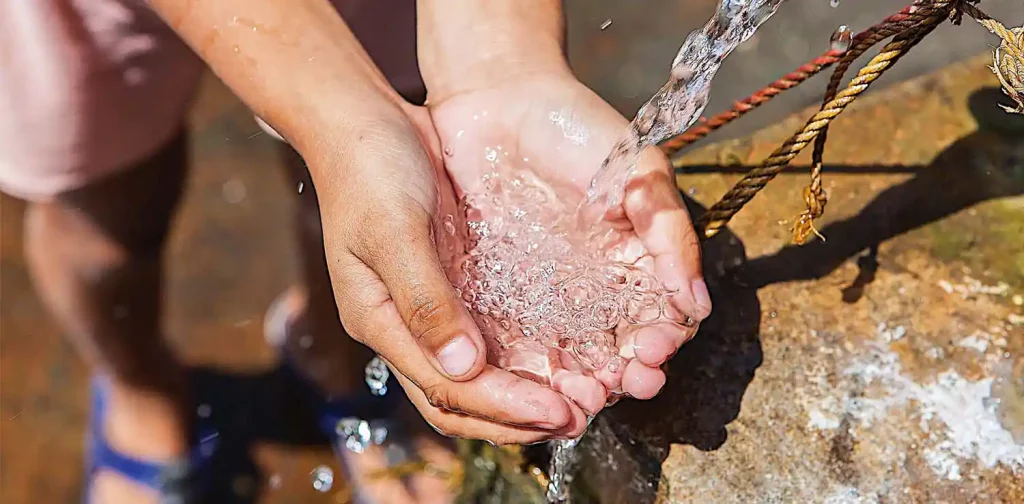 a child’s hand facing upwards to retrieve water from the tap