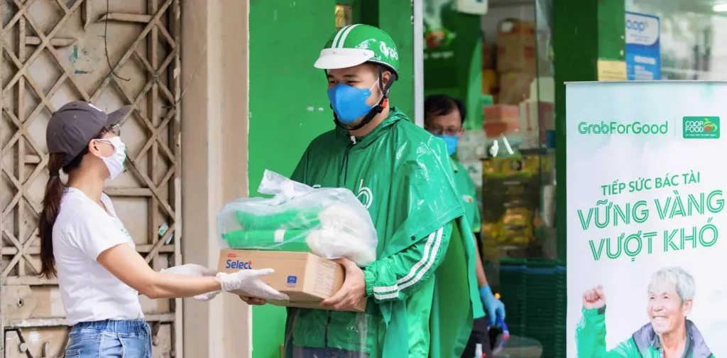 a woman handing a set of care package to a man in green grab uniform for food assistance program