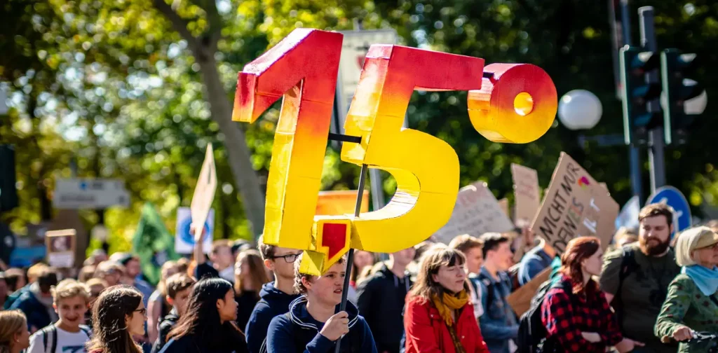 a group of people at climate change protest with a giant 1.5 degree Celsius signage