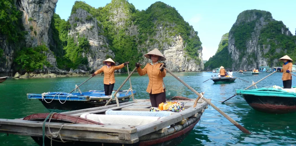 hree fishers in brown shirt are standing on their respective boats in Halong Bay, Vietnam