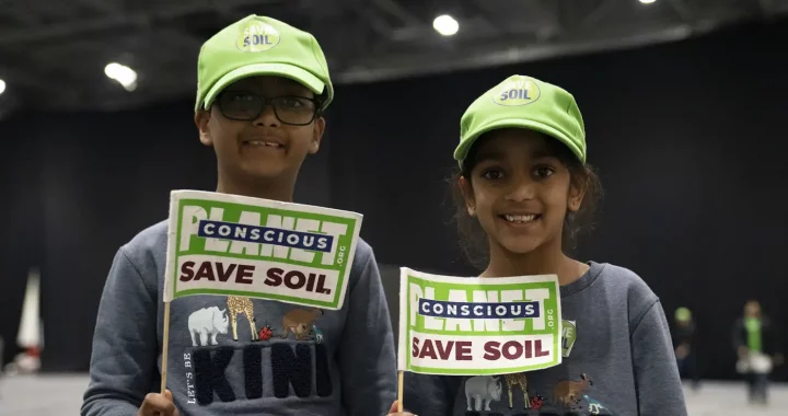 two kids in identical outfits holding a flag that says ‘Save Soil’