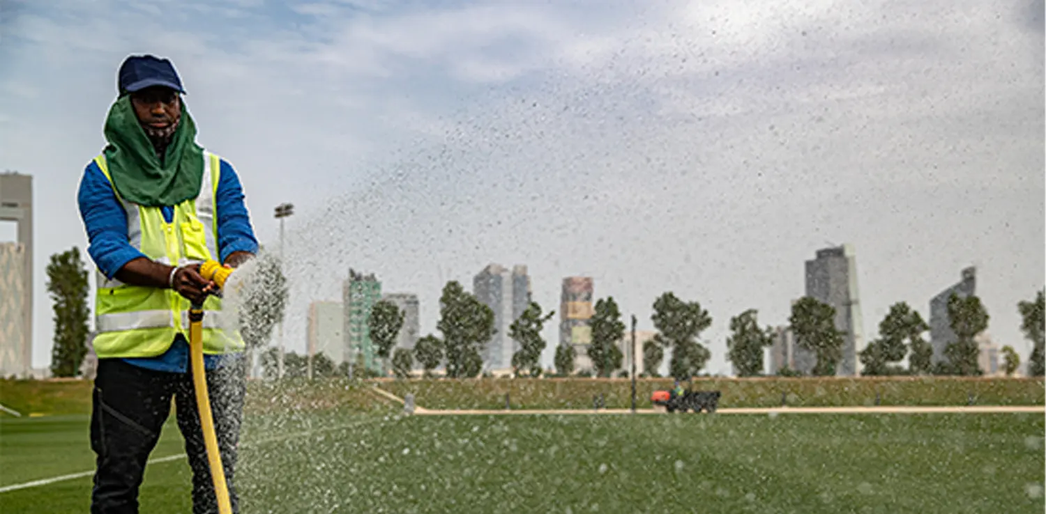 a man watering a green space with a hose