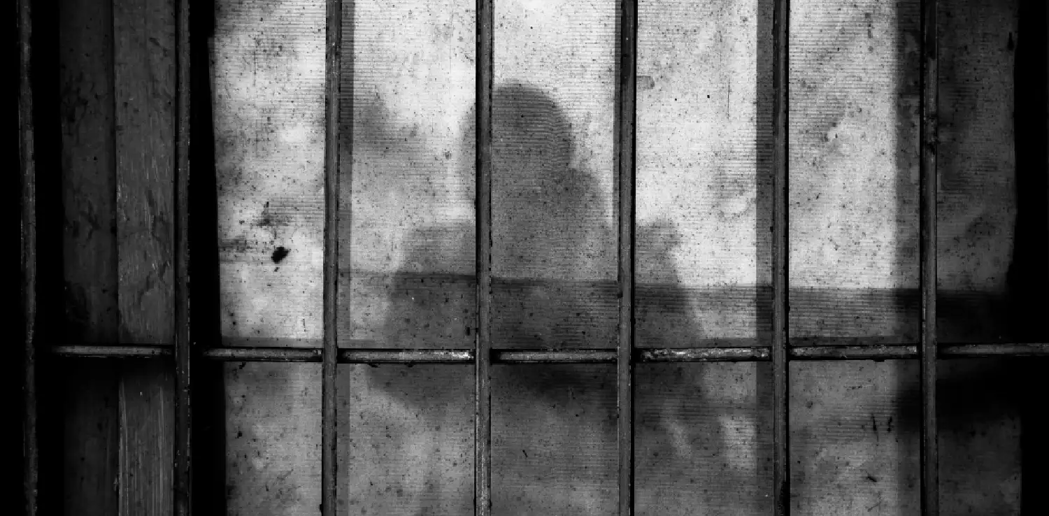 silhouette of a figure behind bars