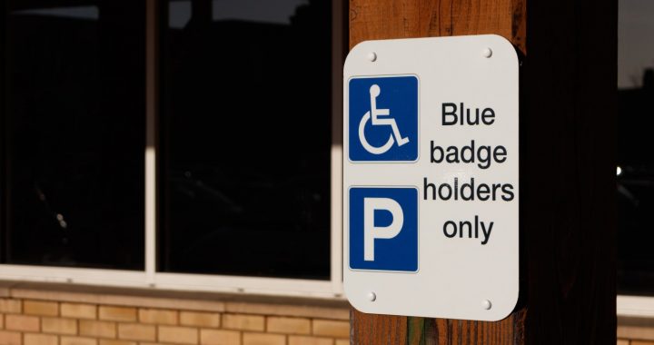 a blue parking sign that reads “Blue badge holders only” indicating designated space for people with disabilities