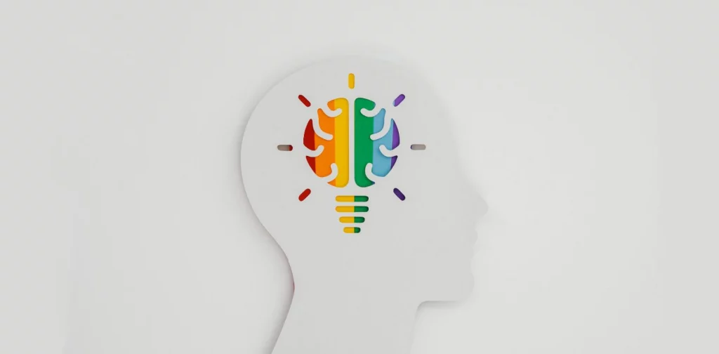 a paper cutout of rainbow brain in a head silhouette