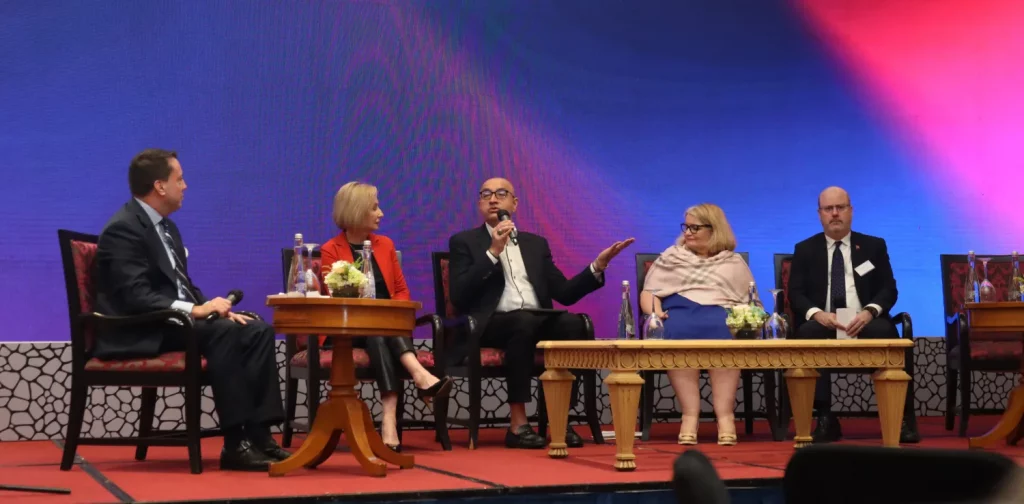 five people on stage in the middle of a plenary session.