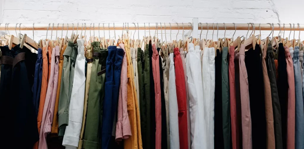 a line of colorful clothing hanging on wooden wall rack