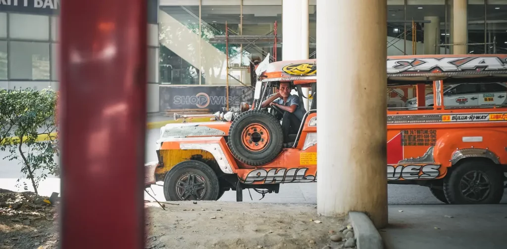 an orange jeepney with a driver inside