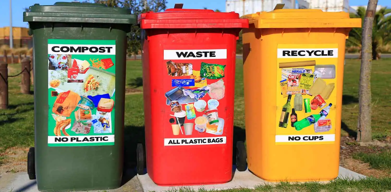 Three big garbage bins in green, red, and yellow for compost, waste, and recycle