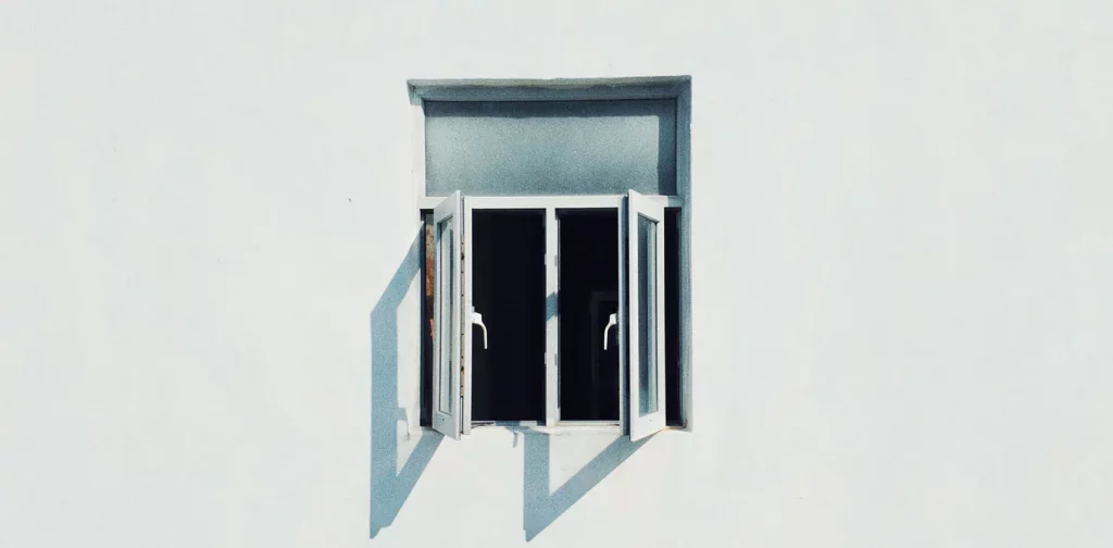 an opened window in the middle of white wall