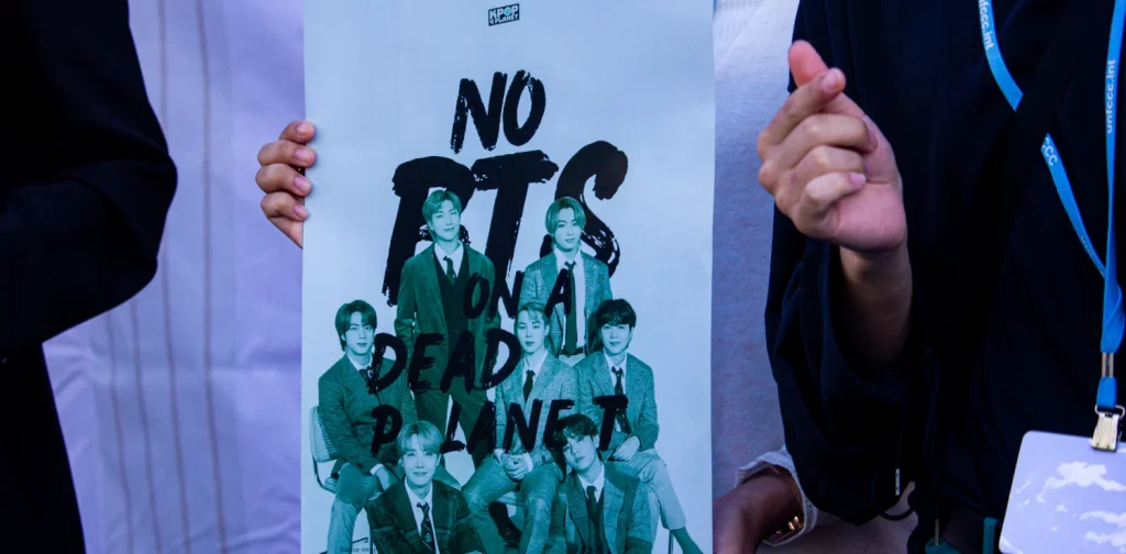 a bts fan showing a poster that says ‘No BTS on A Dead Planet’