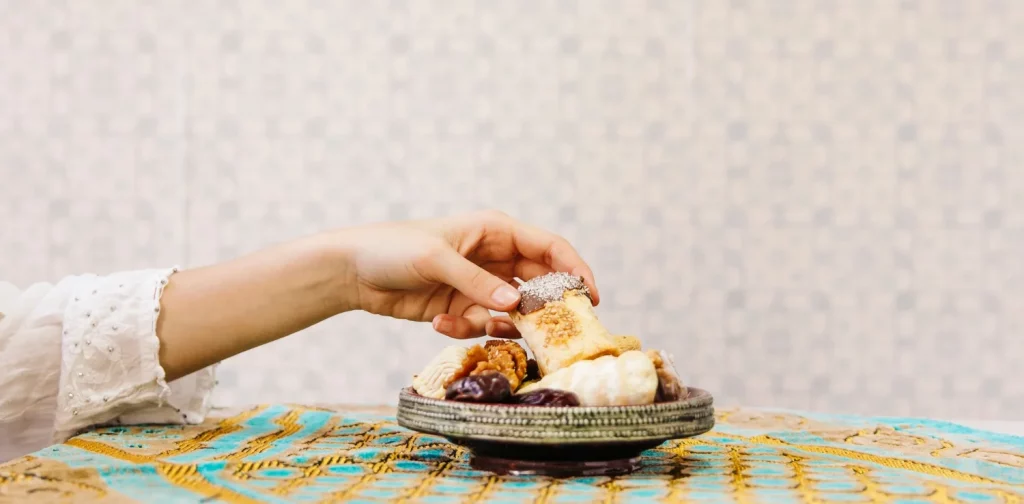 hand taking from a plate of Arabic pastry