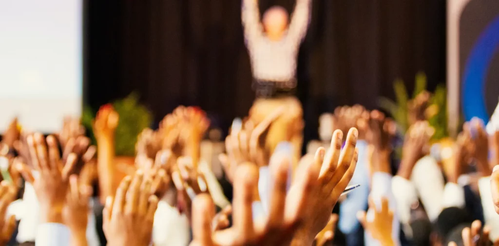 people raising their hands in a conference