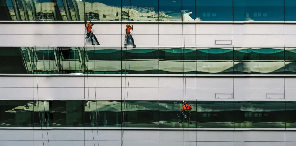 three window cleaners working on a tall building