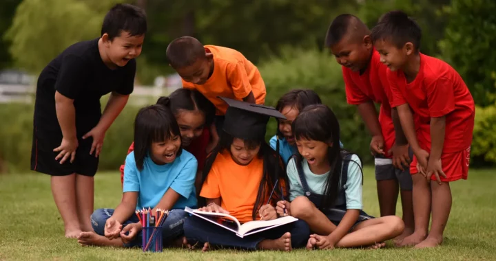 A group of little boys and girls studying together outside at a park