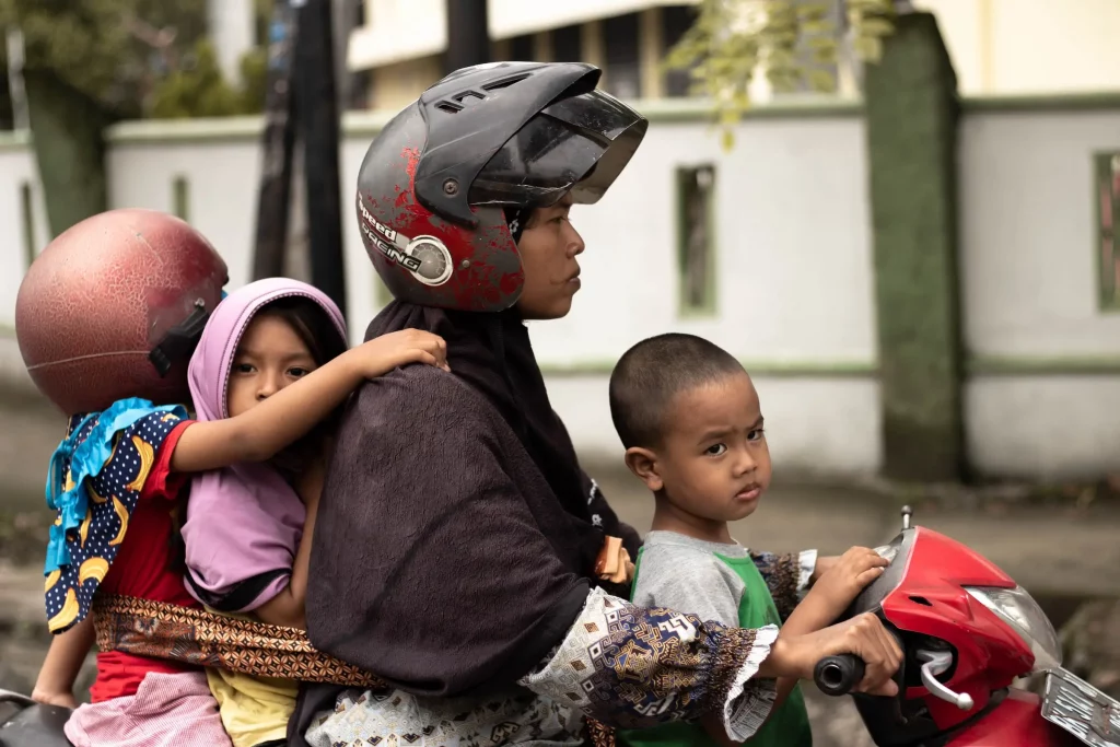 a mother on a motorcycle with three kids