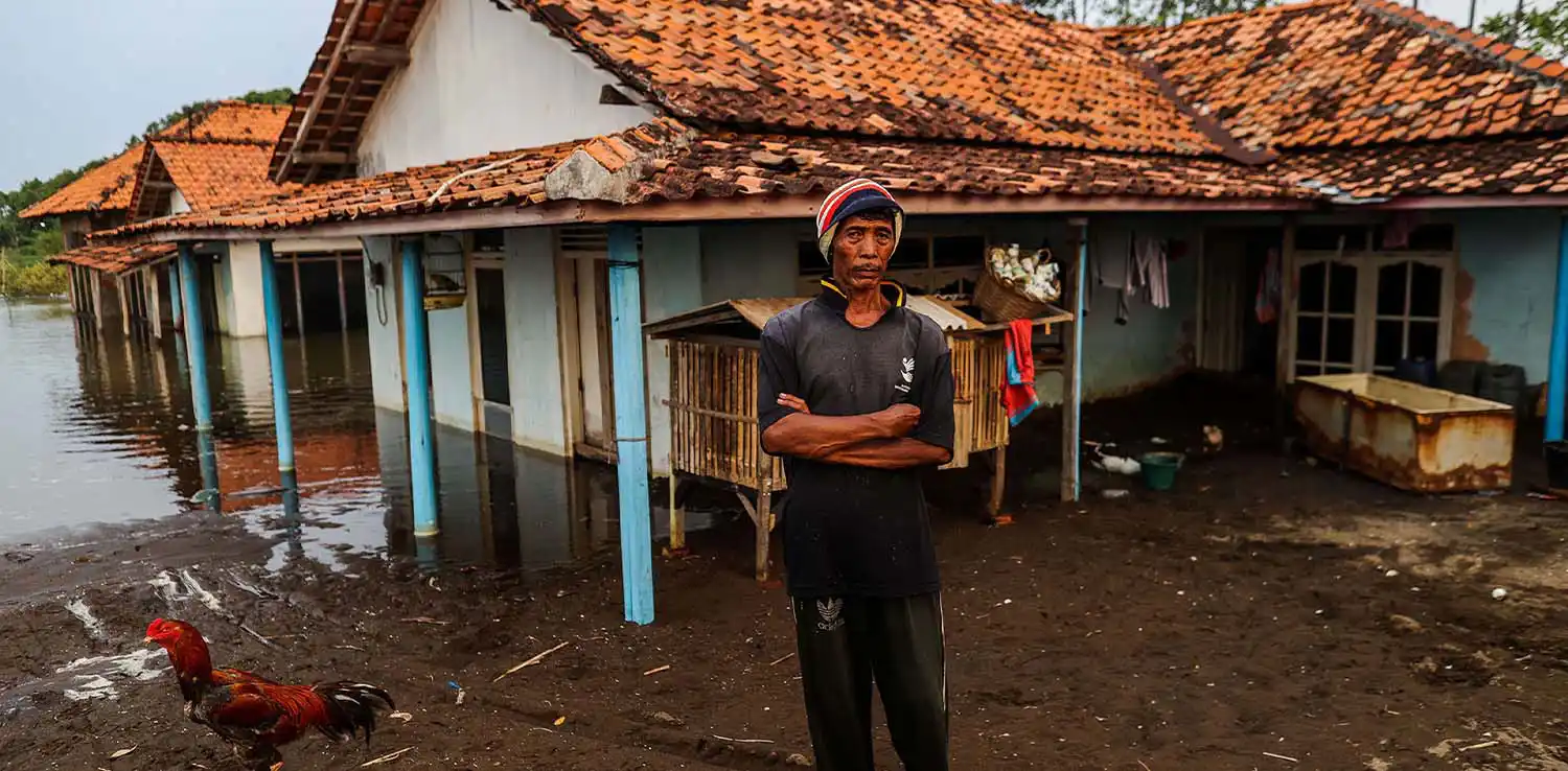 A local resident is standing in front of a sinking house in Pekalongan, Central Java.