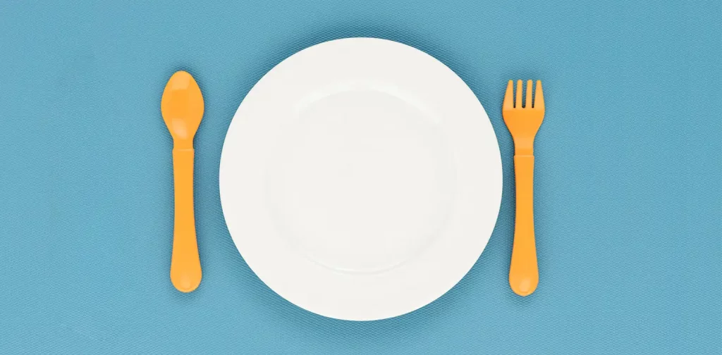 an empty plate with fork and spoon beside it