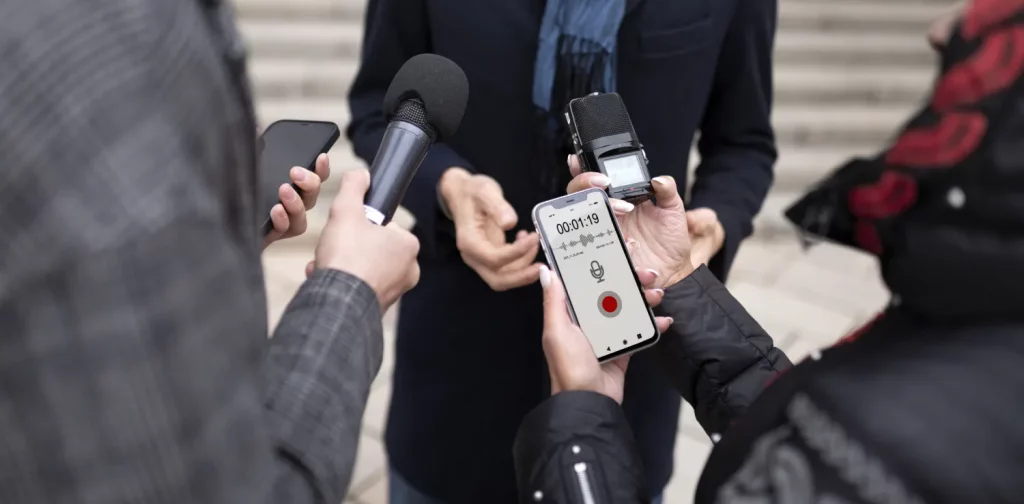 a close up of reporters holding a microphone and recording devices while doing interviews