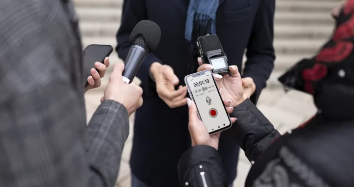 a close up of reporters holding a microphone and recording devices while doing interviews