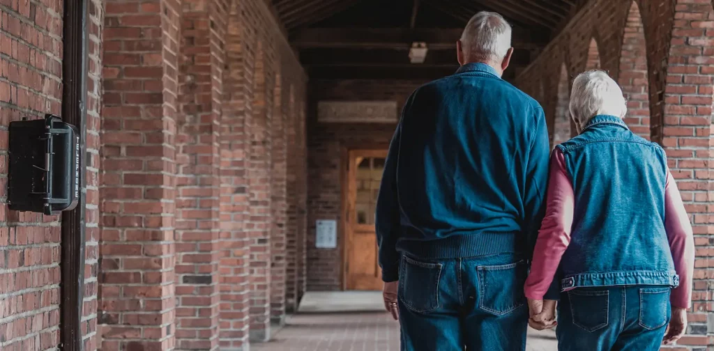 a back view of an elderly couple walking while holding hands