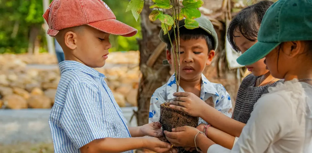three kids holding a sapling
