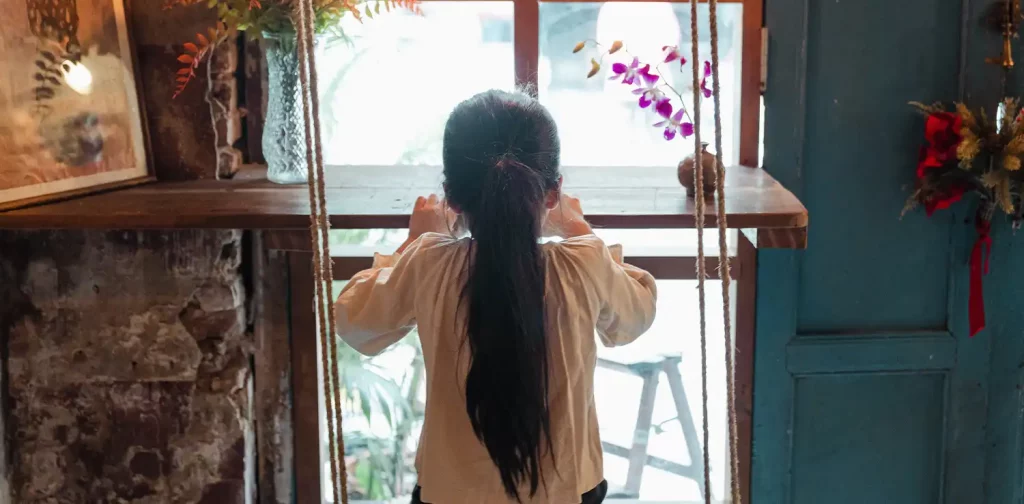 a little girl on a swing against the window