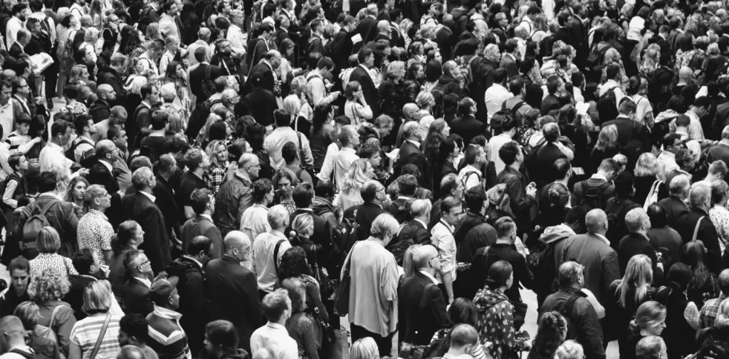 a grayscale photo of crowd of people standing