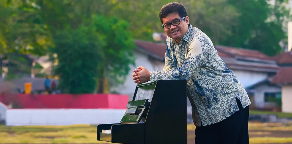 a man, Ananda Sukarlan, is leaning over a piano