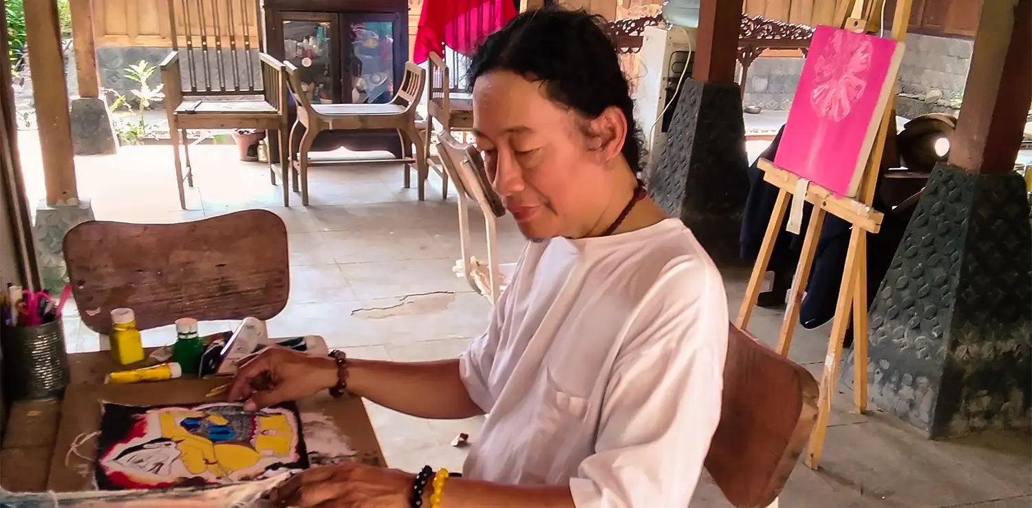 a man, hangno Hartono, is painting wayang at a studio called Omah Budaya Kahangnan