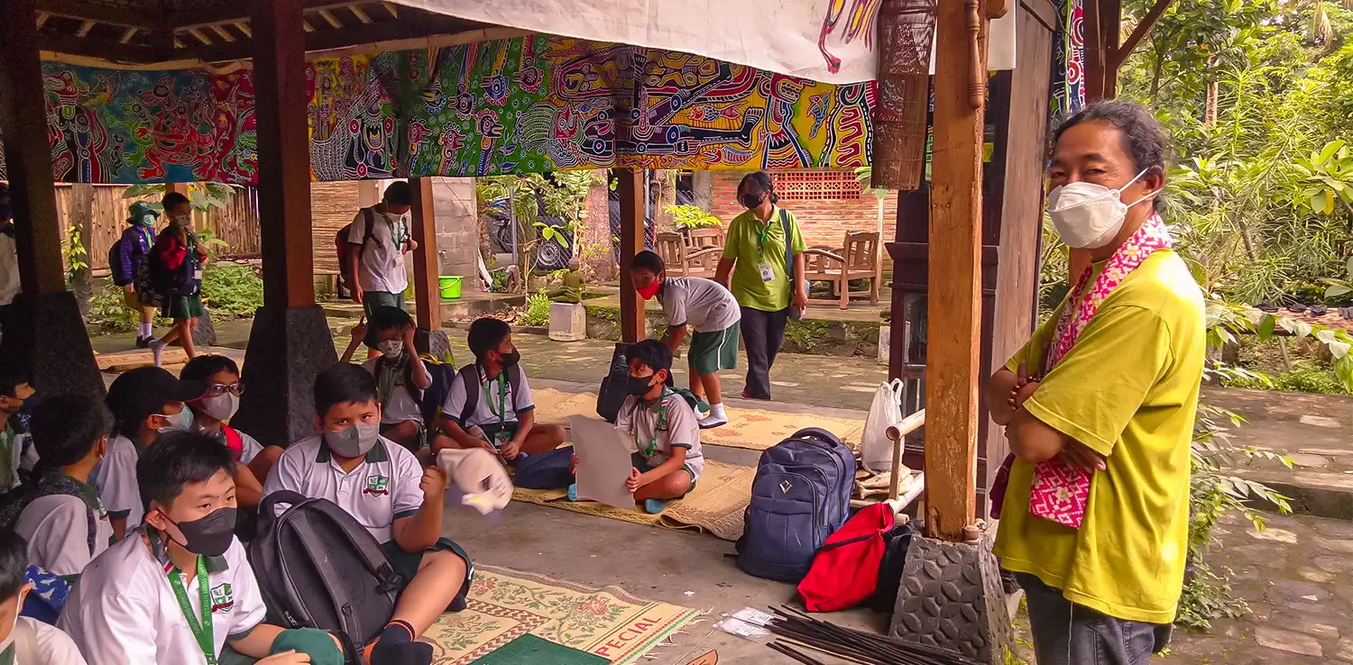 A man, Hangno Hartono, standing in front of kids during a wayang workshop