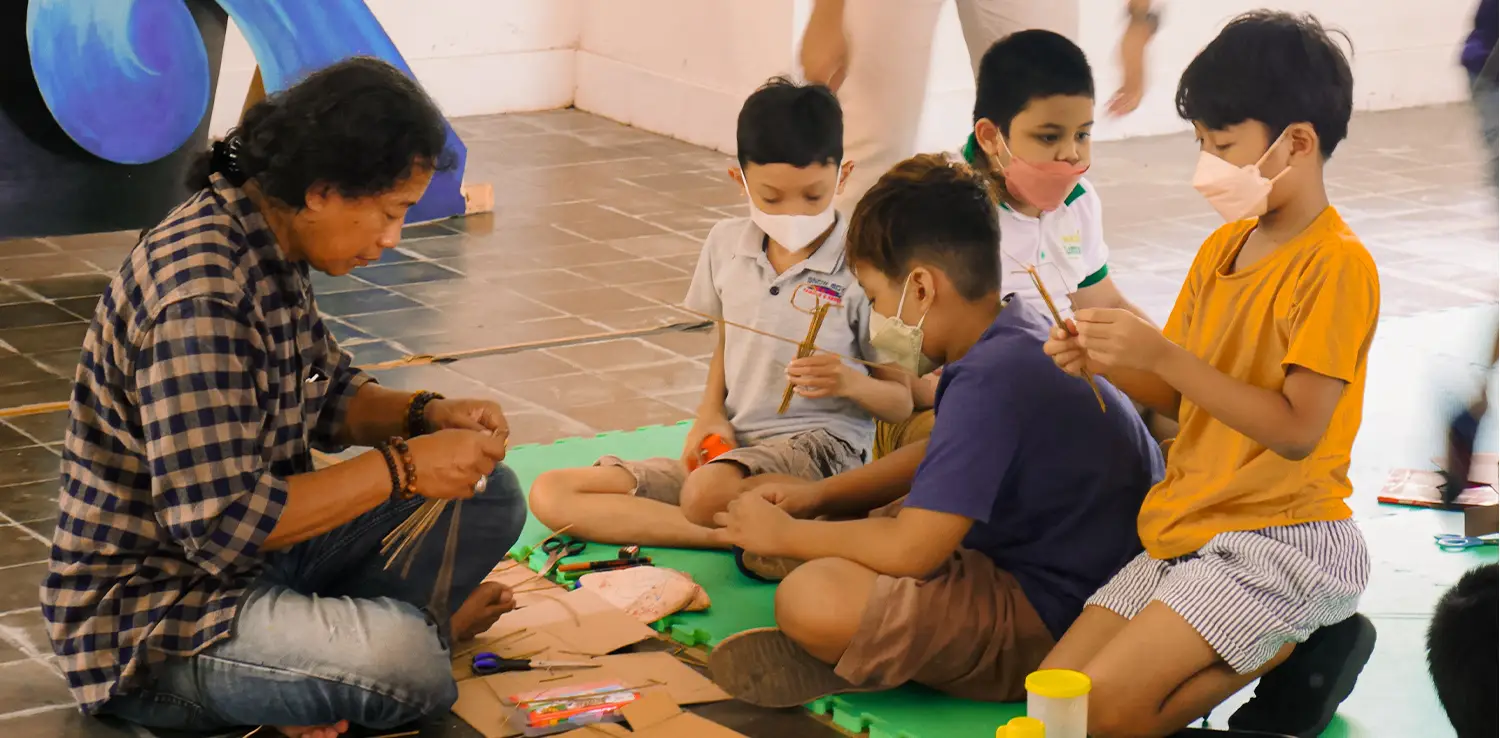 a man, Hangno Hartono, teaching four boys about wayang