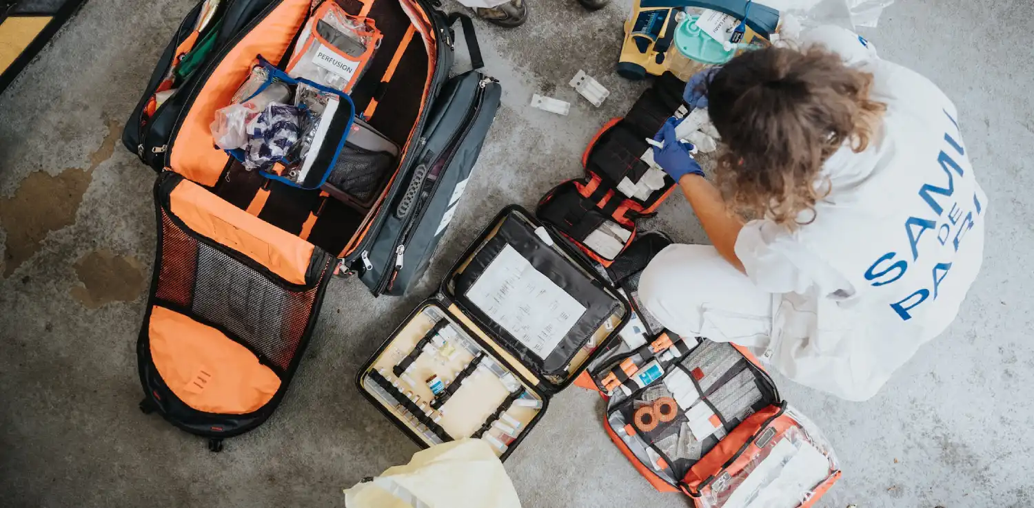 a boy crouching in front of first-aid-kit backpacks