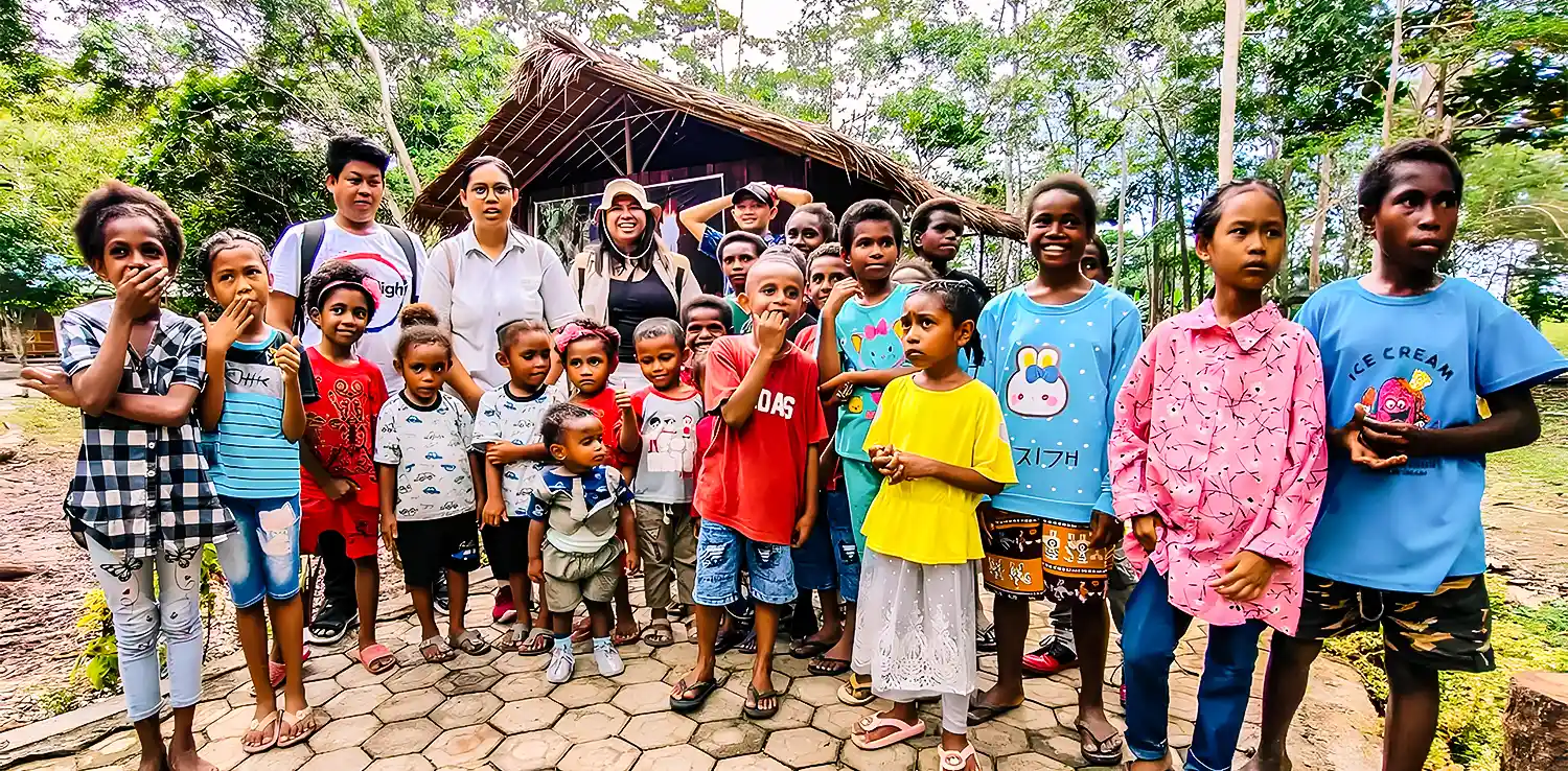 children of papua and several adults smiling at the camera