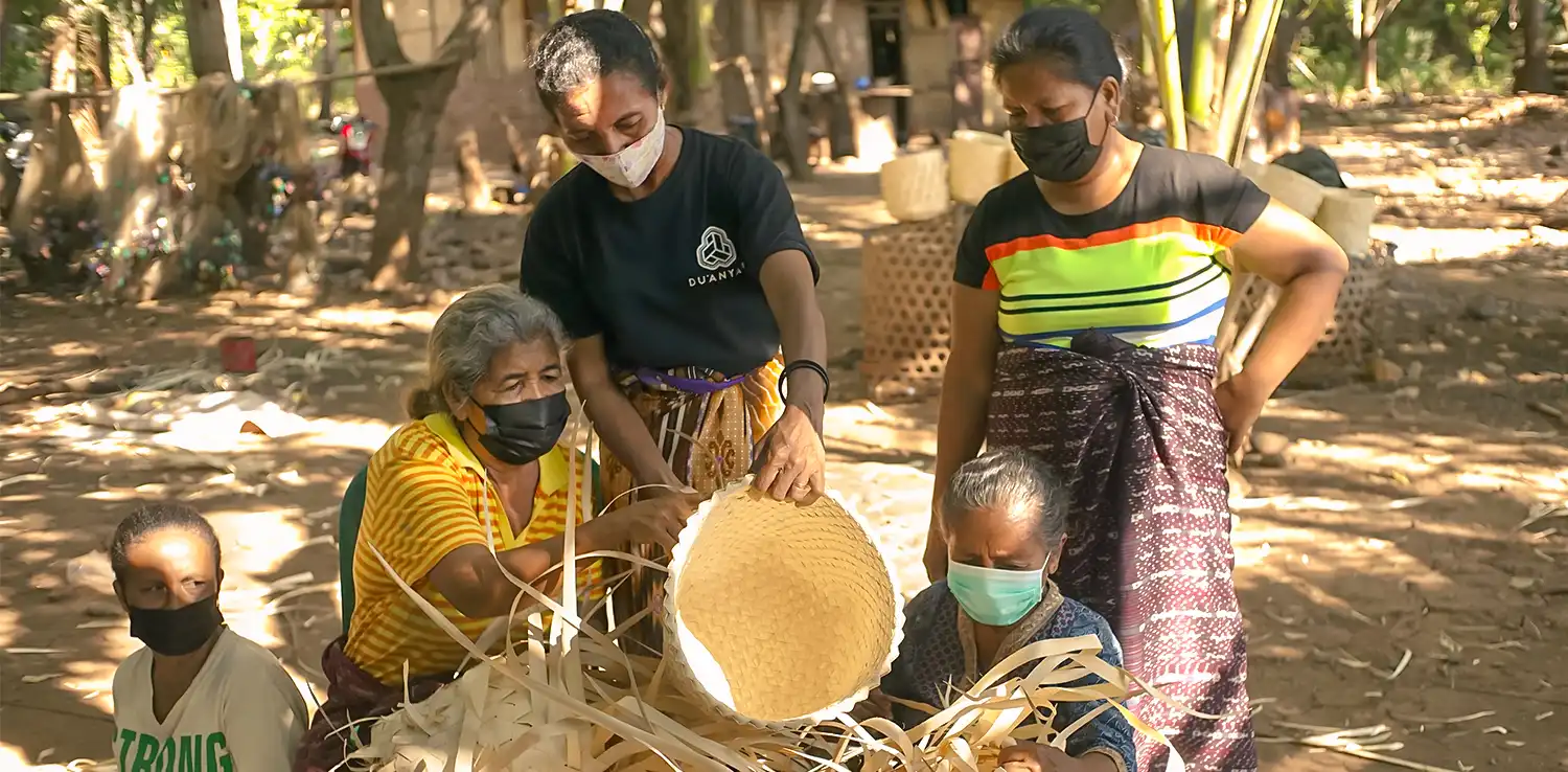  five women wearing masks making a woven basket