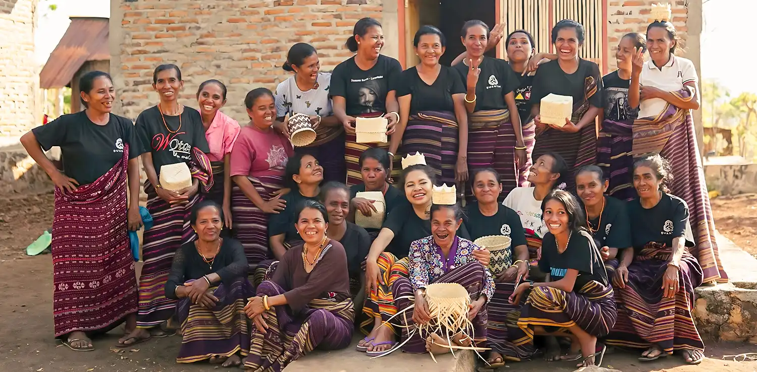 a group of women wearing Indonesian traditional woven garment smiling at the camera.