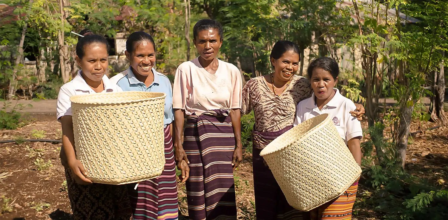 five women holding two woven baskets they made smiling at the camera