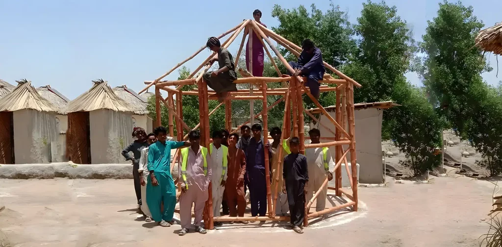 a group of young men standing inside a building structure made of bamboos, a few of them are hanging on the roof