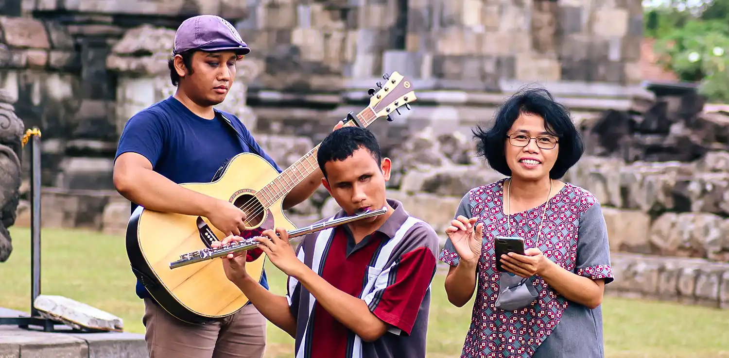 two men playing a guitar and a recorder while a woman standing next to them