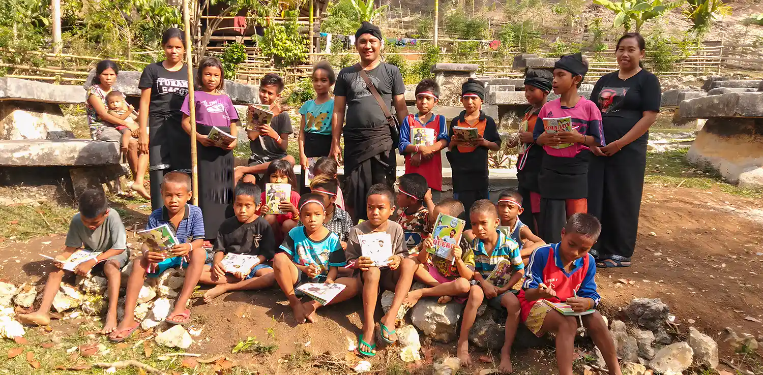  a group of children are posing for the camera, each of them is holding a book. Half of them are standing, and half others are sitting.