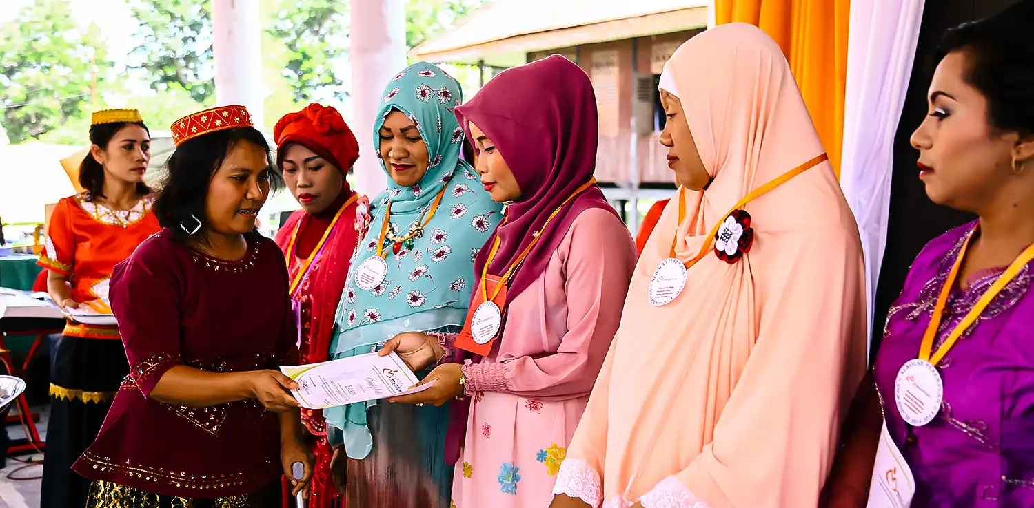 several women are standing in line while Lian Gogali gives a certificate to one of them