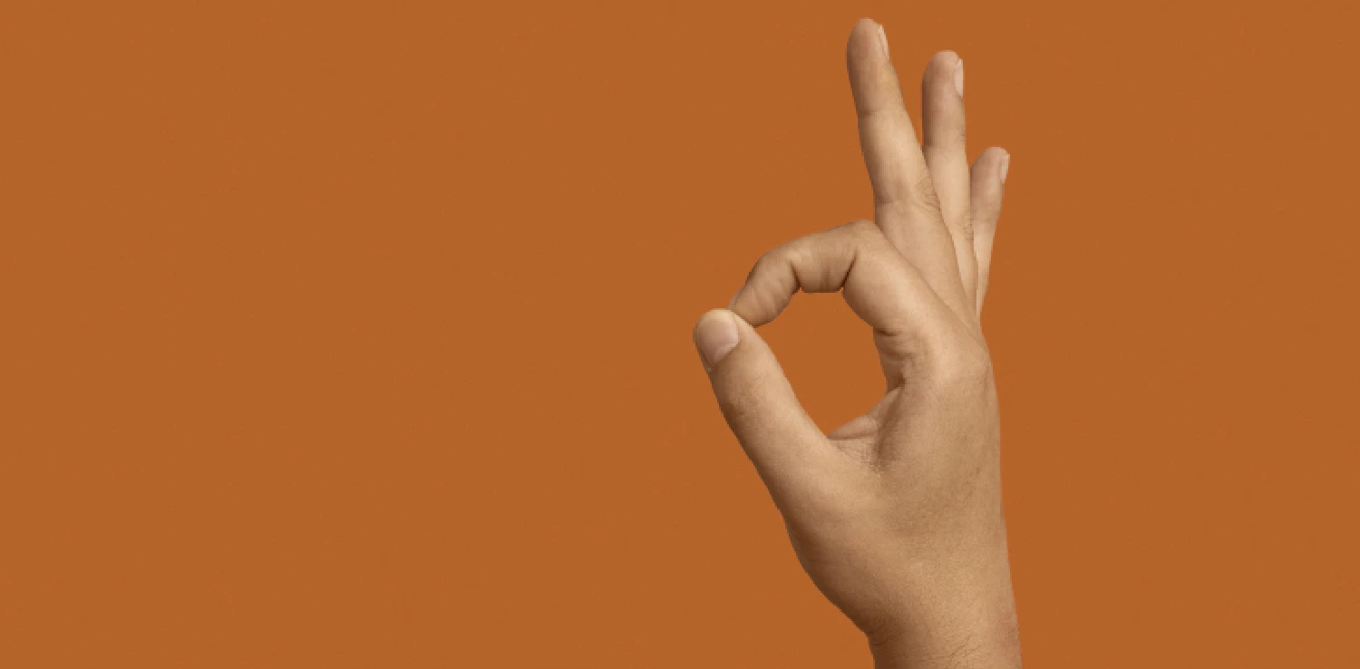 a hand doing an OK pose against an orange background