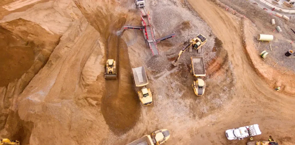 an aerial photo of trucks in the middle of sand field