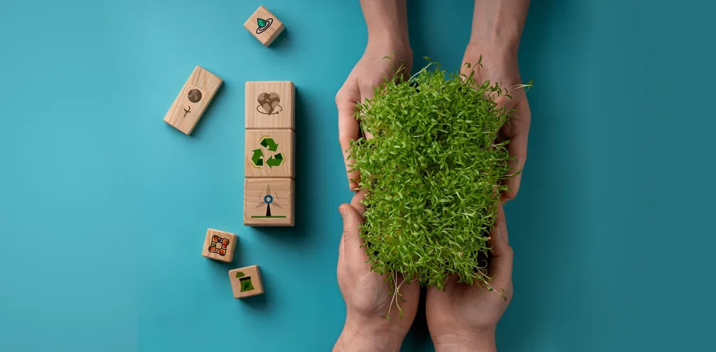 two hands exchanging plants with blocks with sustainability symbols scattered around them